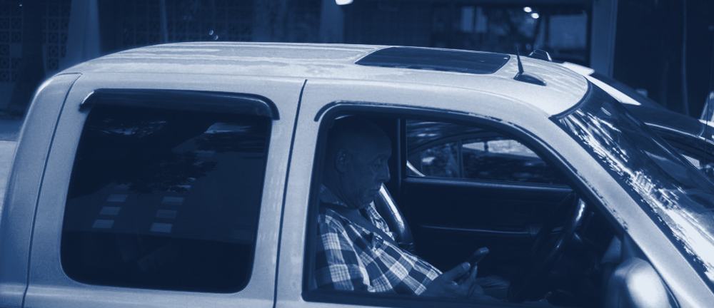 A business owner in a pickup truck reading a text